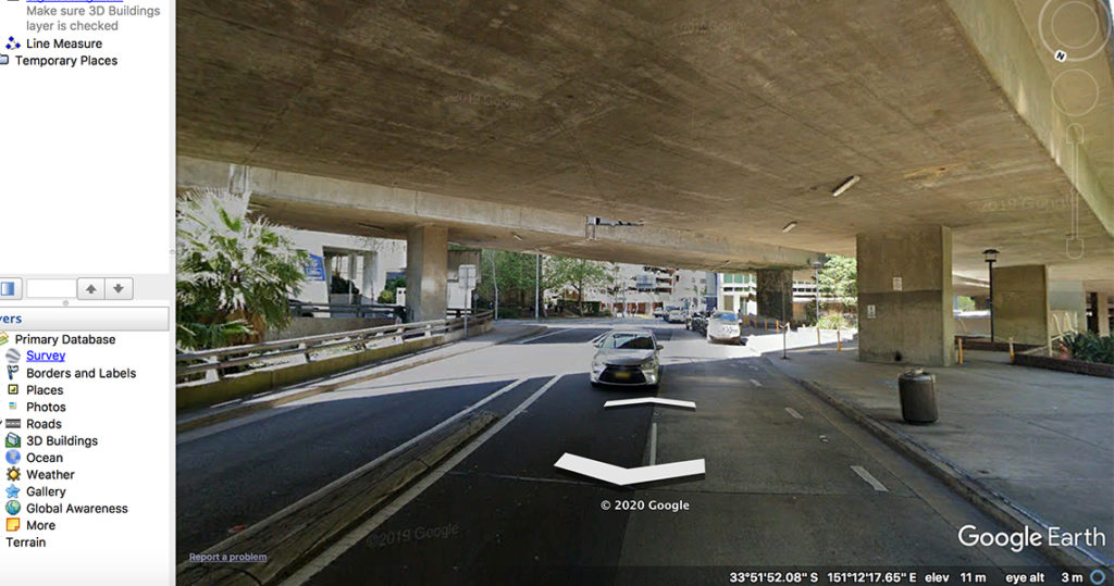 Colour photo of highway underpass with a palm tree fo the left hand side.